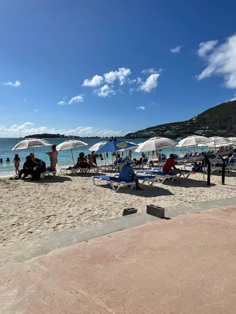 Sunny Great Bay Beach with umbrellas and swimmers a few steps from Thirsty Pirate Beach Bar