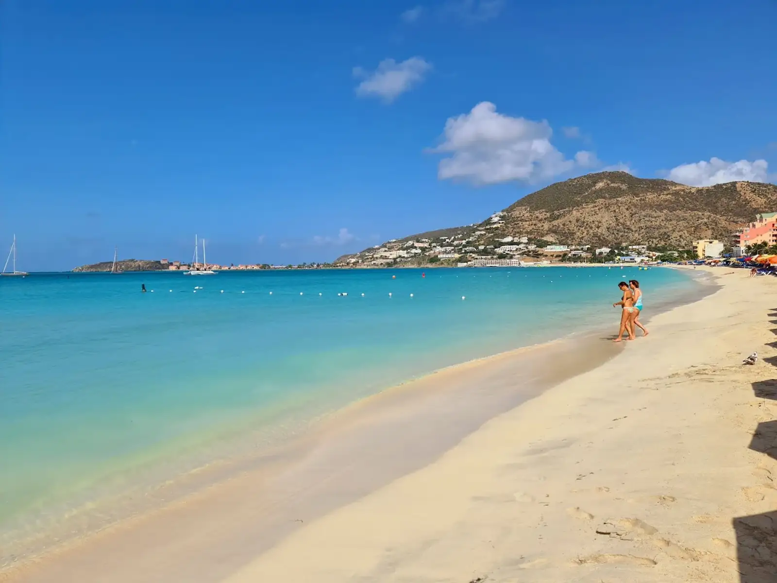 Couple walking the turquoise shoreline of Great Bay Beach in Philipsburg, Sint Maarten