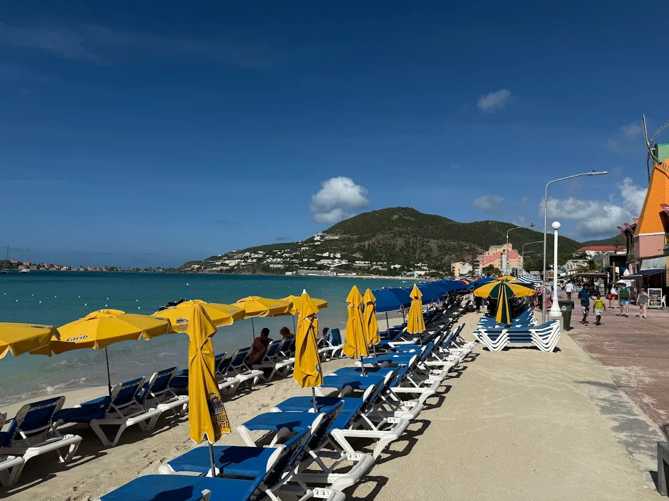 Rows of blue beach loungers and yellow umbrellas on Great Bay Beach along the Philipsburg boardwalk