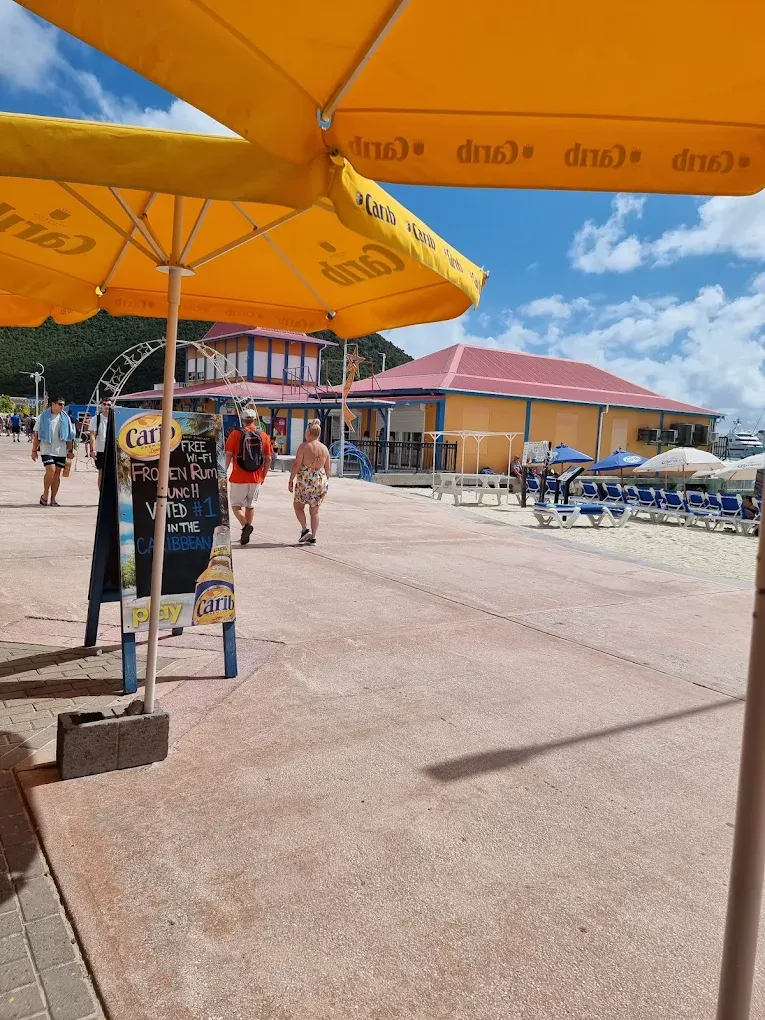 Front Street boardwalk with a Carib umbrella and a "Frozen Rum Punch — Voted #1 in the Caribbean" sign outside Thirsty Pirate