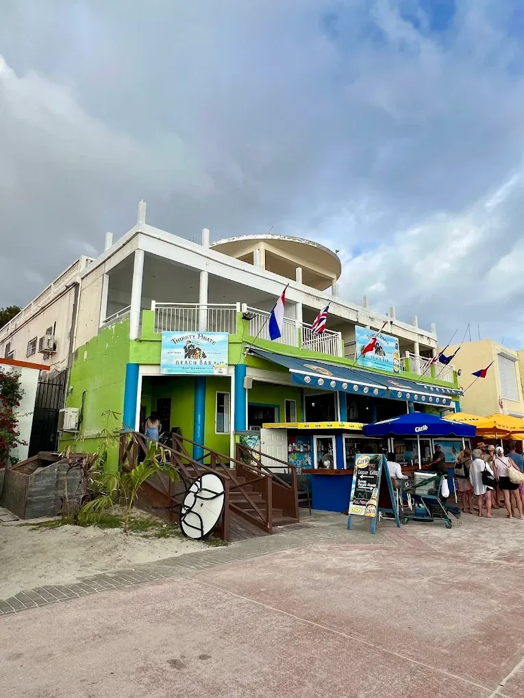 The green and blue Thirsty Pirate Beach Bar building flying Caribbean flags above the Philipsburg boardwalk