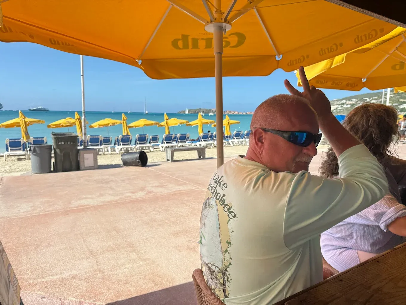 Guest relaxing at Thirsty Pirate Beach Bar with a cruise ship and Great Bay beach loungers in the background, Sint Maarten